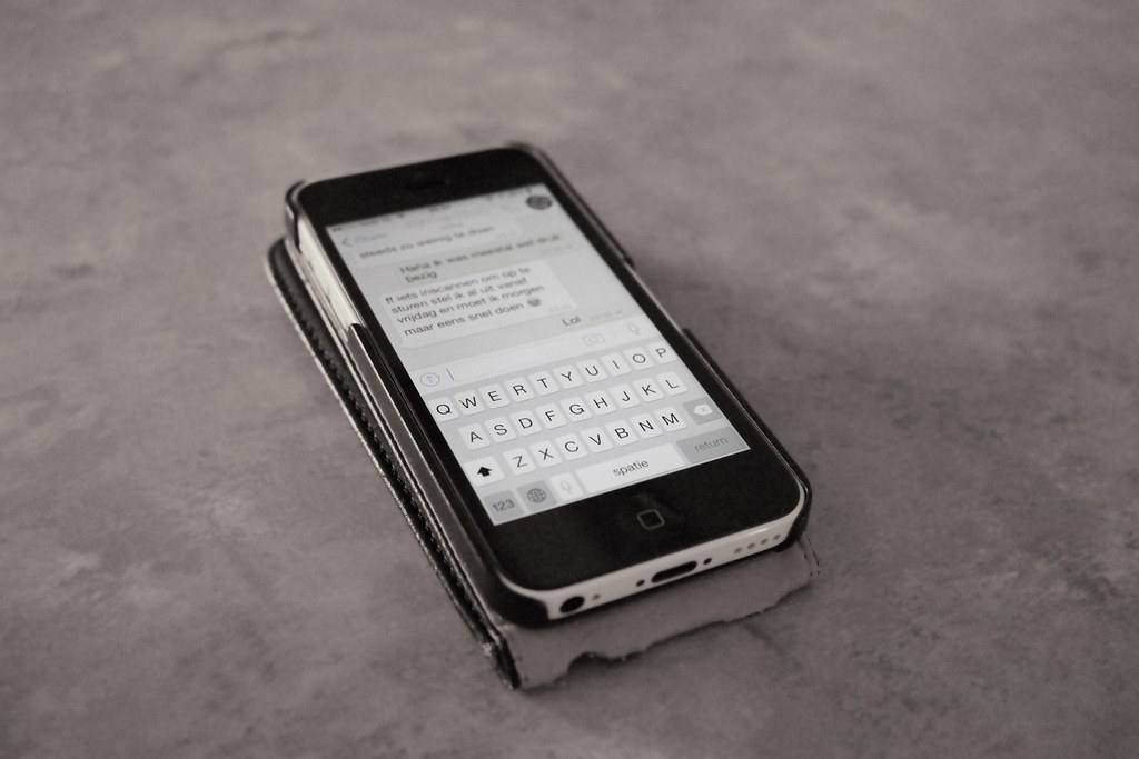 iPhone s otevřeným vláknem zpráv leží na betonové desce