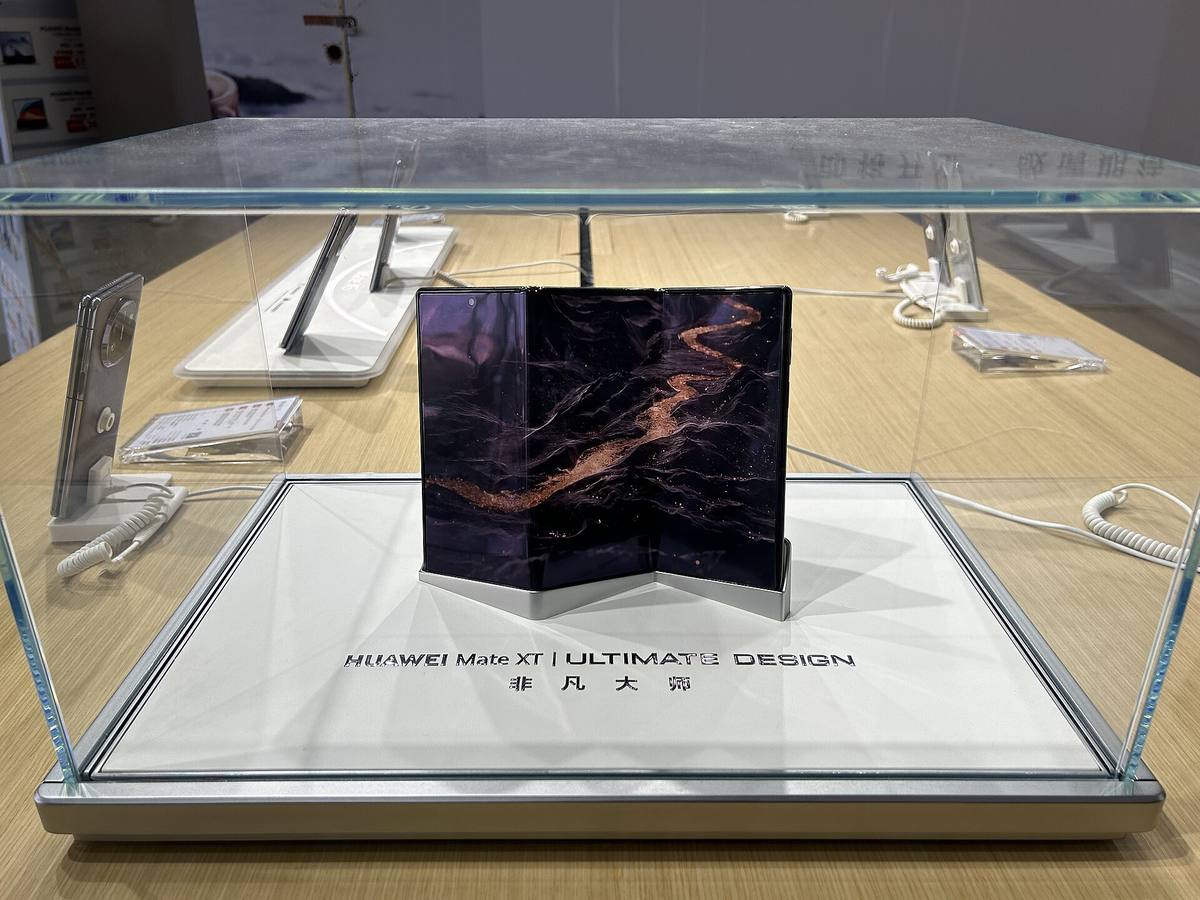 Trojskládací telefon Huawei Mate XT ve skleněné vitríně prodejny