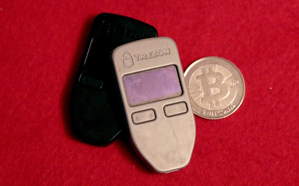 Dvě hardwarové peněženky Trezor a fyzická mince s bitcoinem