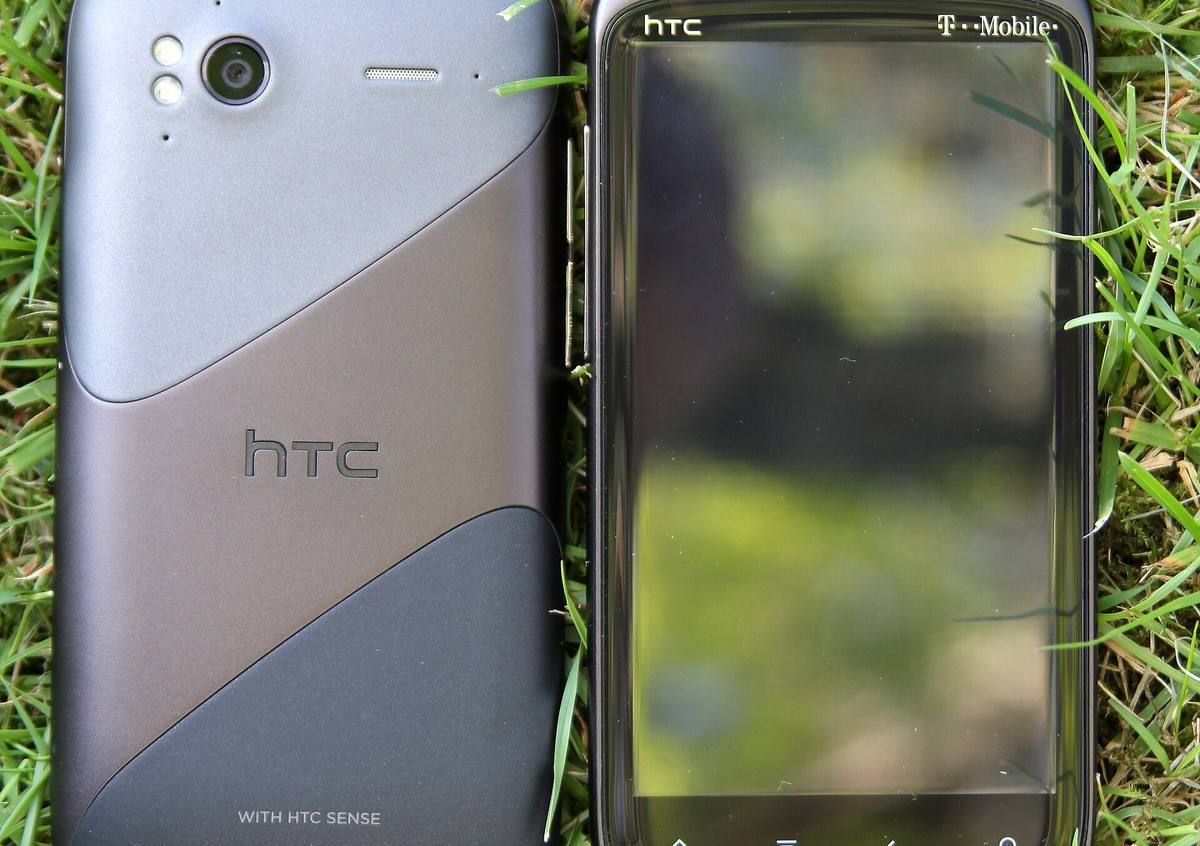 Dva telefony HTC Sensation položené v trávě, jeden čelem a druhý zády vzhůru