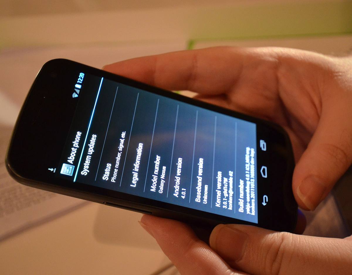 Samsung Galaxy Nexus držený v ruce, na displeji domovská obrazovka Androidu 4.0