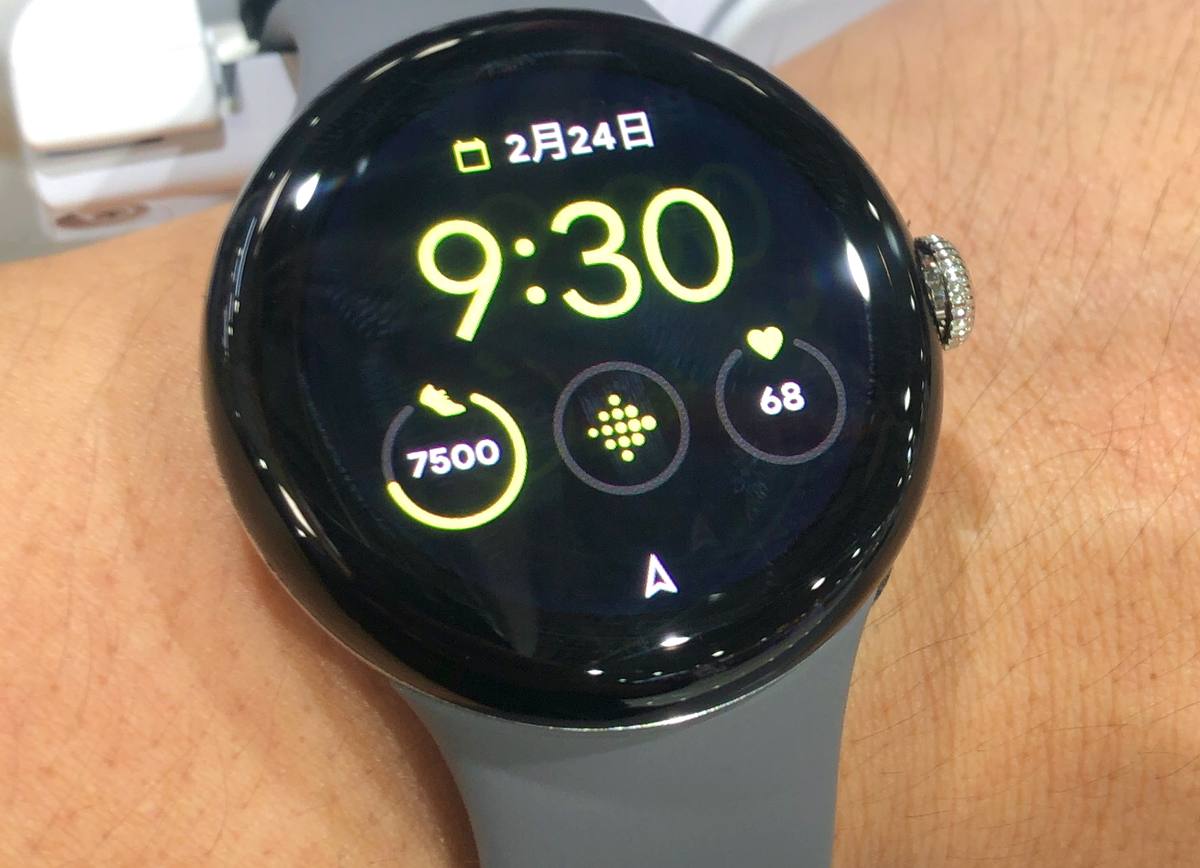 Kulaté hodinky Google Pixel Watch s tmavým ciferníkem a šedým řemínkem na zápěstí