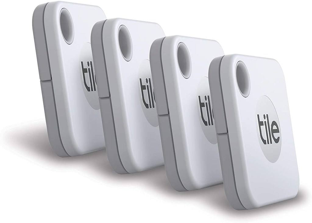 Čtyři bílé bluetooth přívěsky Tile Mate leží na dřevěné desce