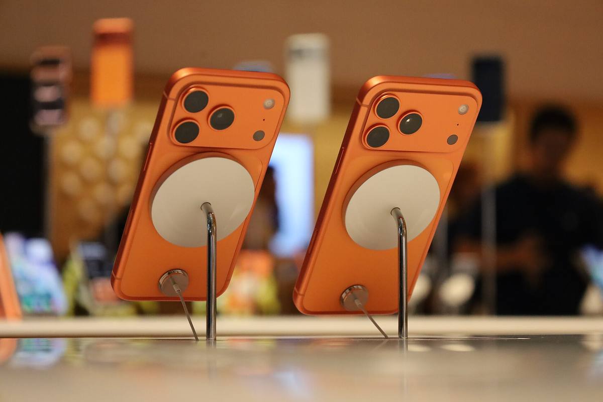 Dva oranžové iPhony 17 Pro na stojáncích v prodejně