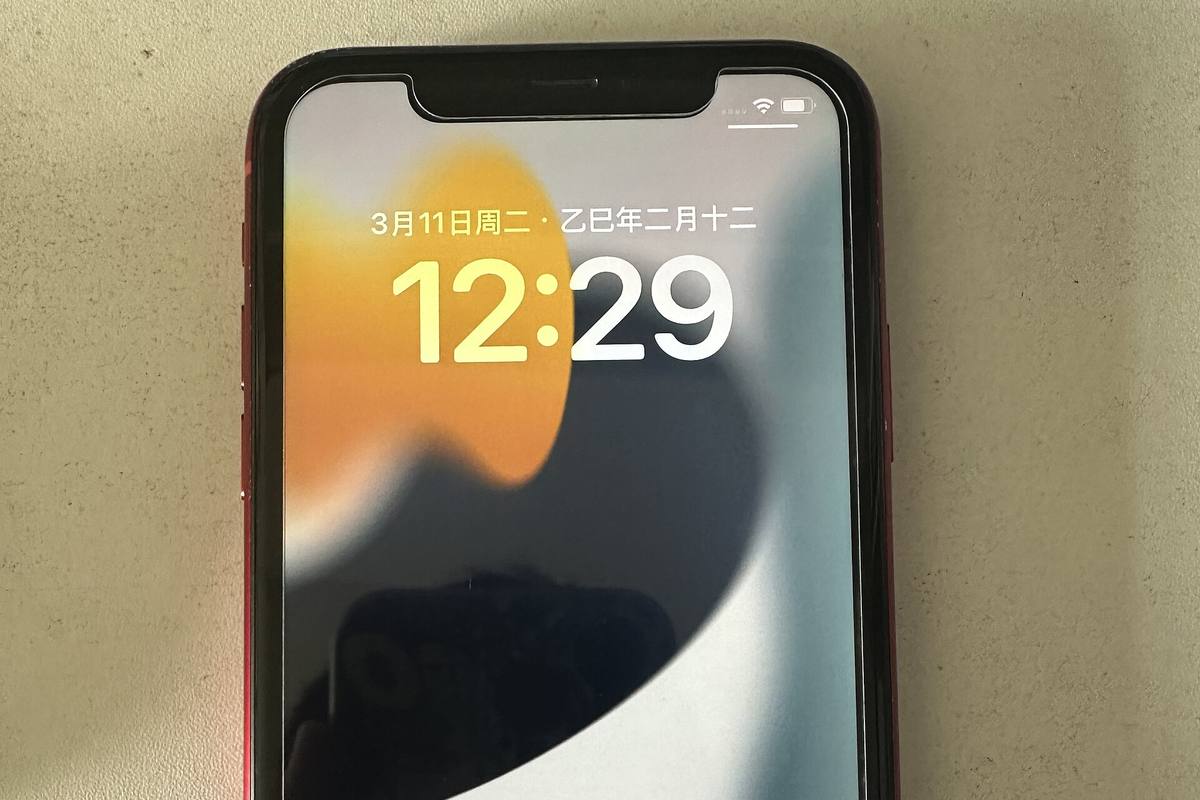 Přední strana červeného iPhonu XR se zamčenou obrazovkou a výřezem nahoře