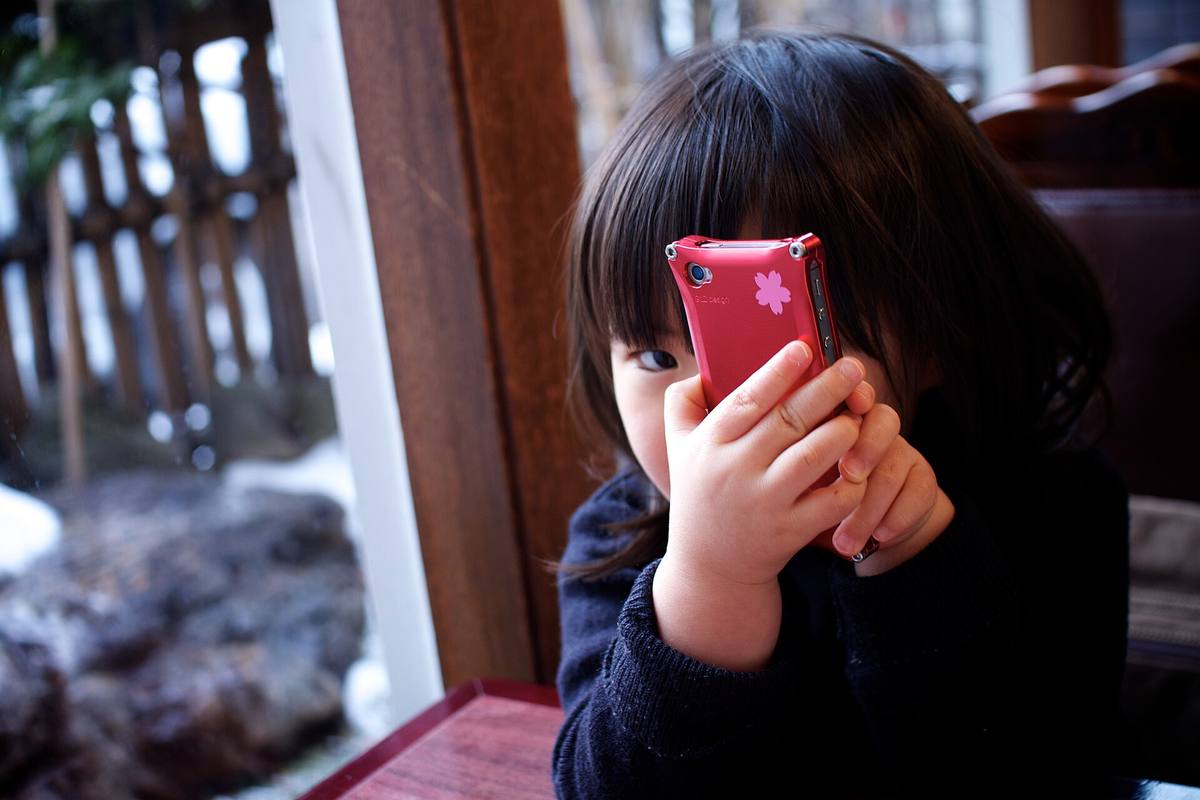 Dítě drží v ruce iPhone a dívá se na displej