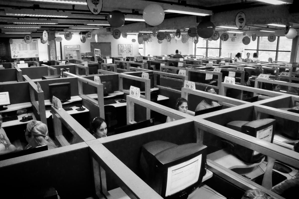 Řady pracovních boxů s monitory a operátorkami se sluchátky v call centru