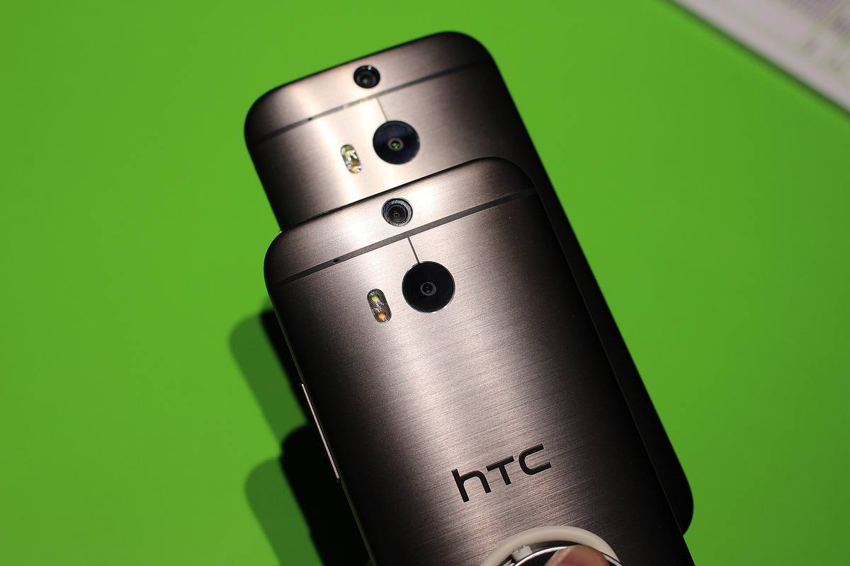 Záda dvou telefonů HTC One (M8) na zeleném podkladu