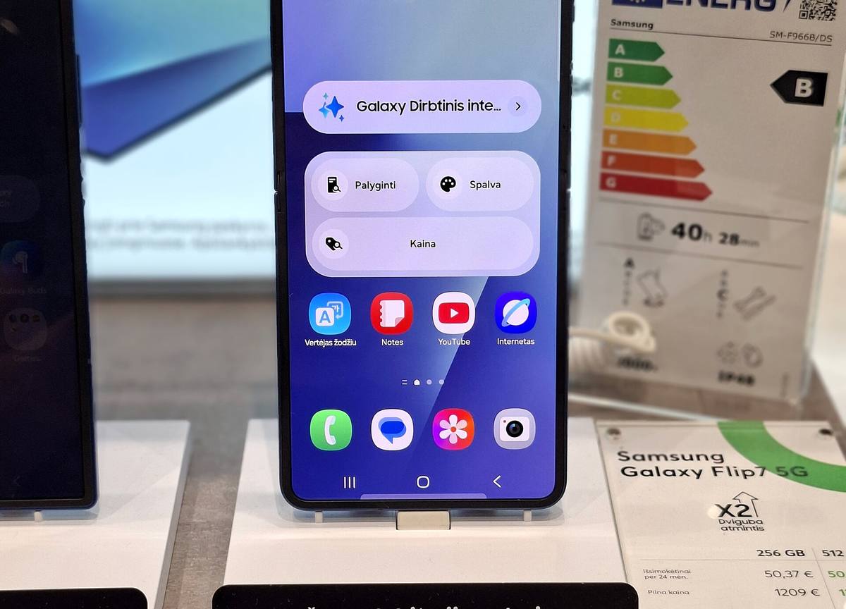 Skládací telefon Samsung Galaxy Z Flip7 rozevřený v prodejní expozici, vedle něj energetický štítek a cenovka